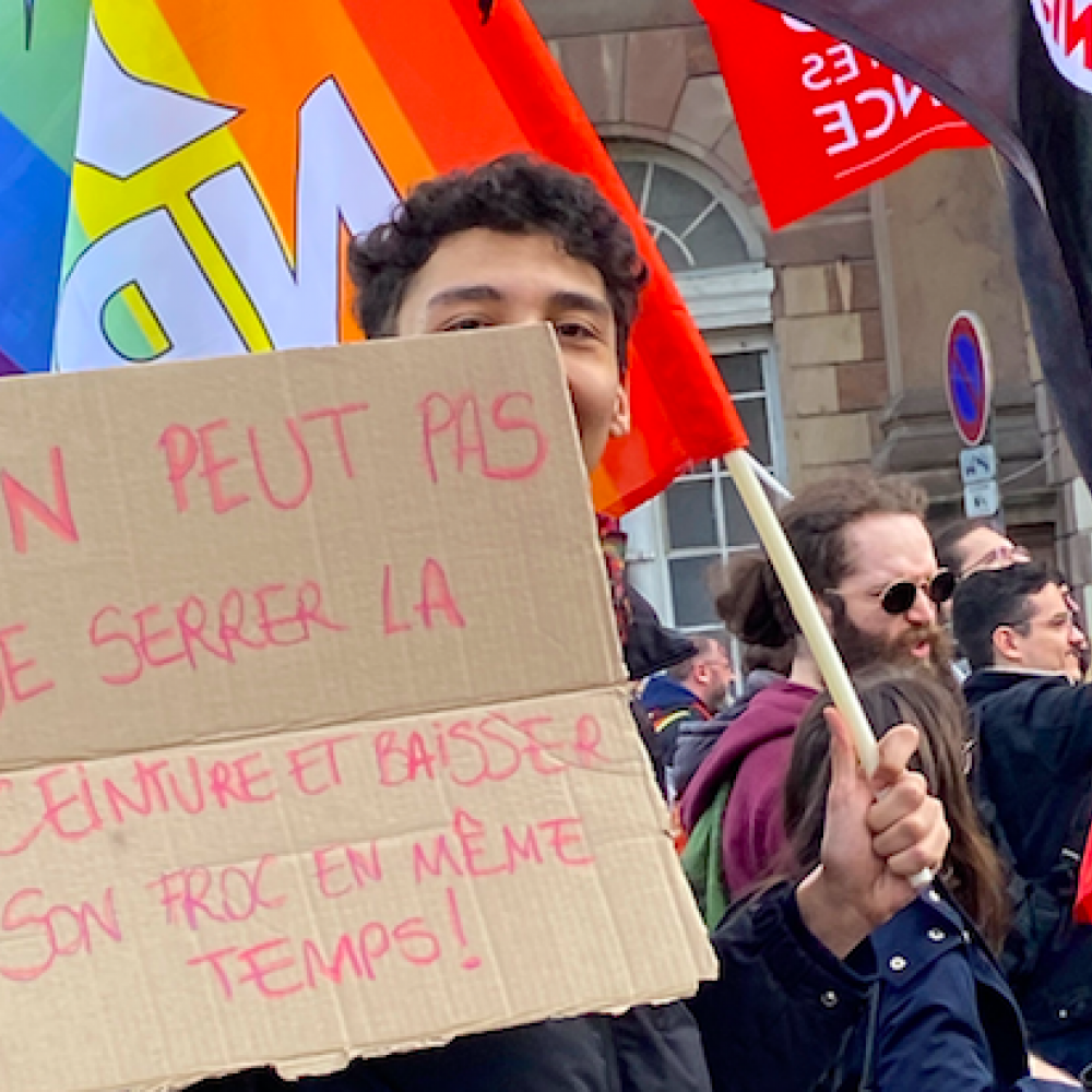 Isaac associe slogan railleur et drapeau du Nouveau parti anticapitaliste aux couleurs LGBTQ.  © Camille Aguilé