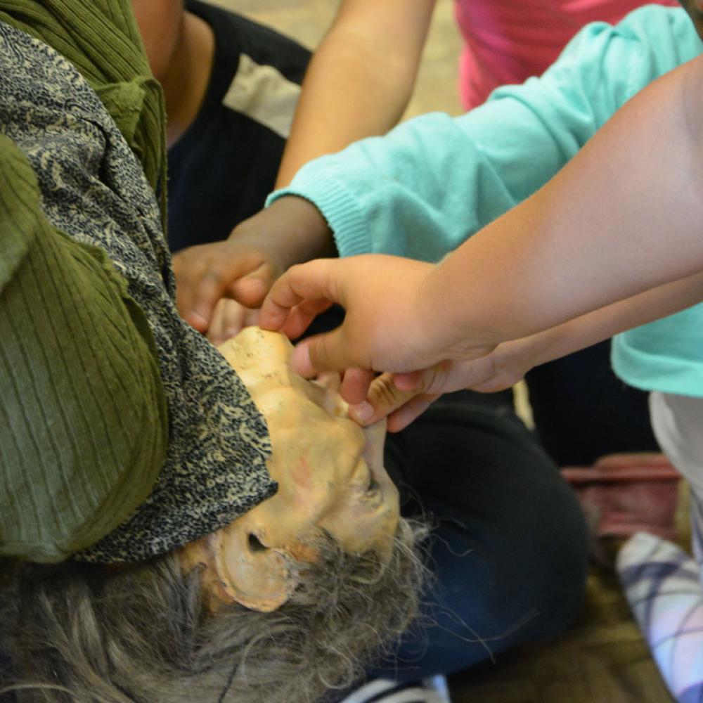 Les enfants, partagés entre peur et fascination, veulent toucher la marionnette pour vérifier qu'elle n'est pas vivante.